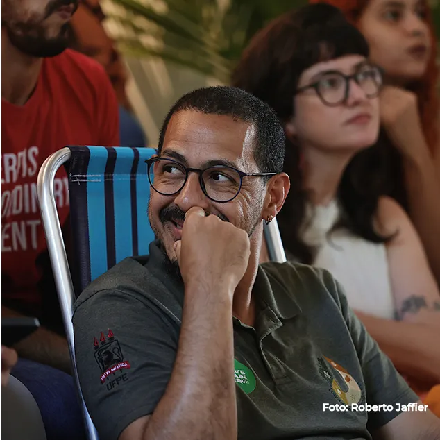 Homem de óculos ouve atentamente na plateia