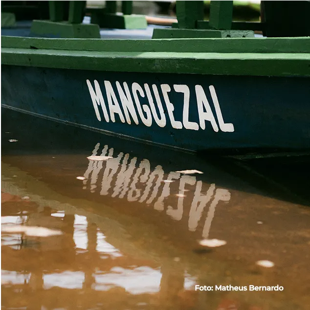 Barco com a inscrição “Manguezal” refletido na água