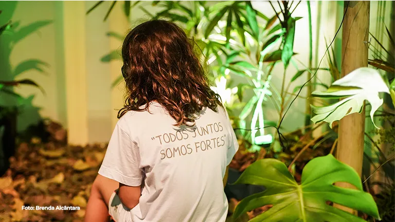 Criança de costas explora a instalação de plantas
