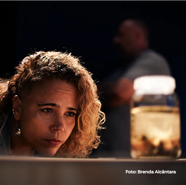Mulher observa uma peça iluminada em vitrine escura