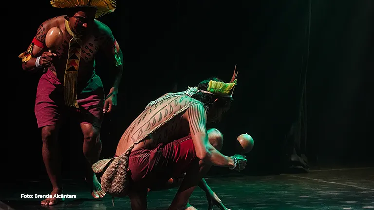 Artistas em performance com adereços de palha no palco