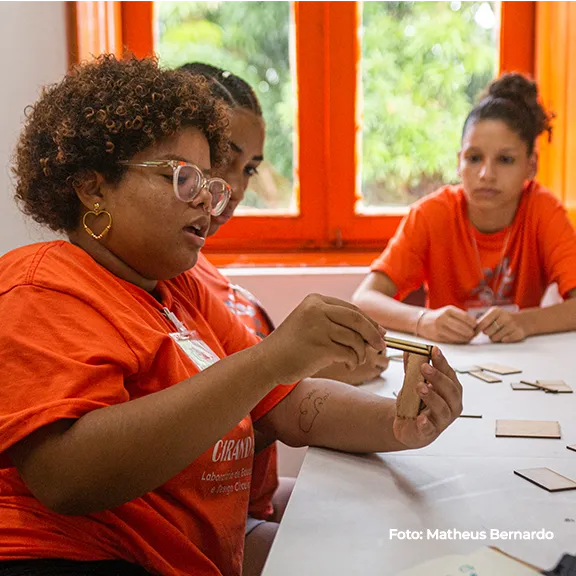 Jovem monta uma peça de madeira durante a oficina de design