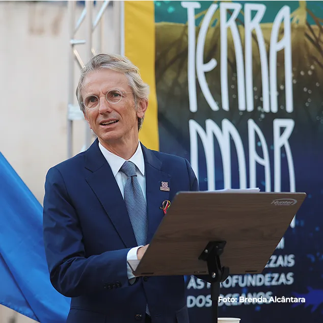 Homem de terno discursa diante do painel da exposição Terra-Mar