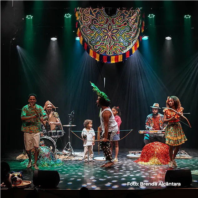 Espetáculo no palco, com músicos e um grande adorno circular