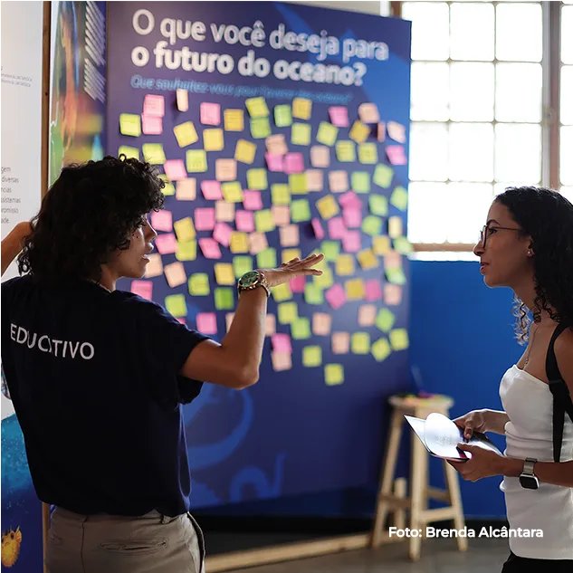Mediadora aponta o painel coberto de post-its sobre o futuro do oceano