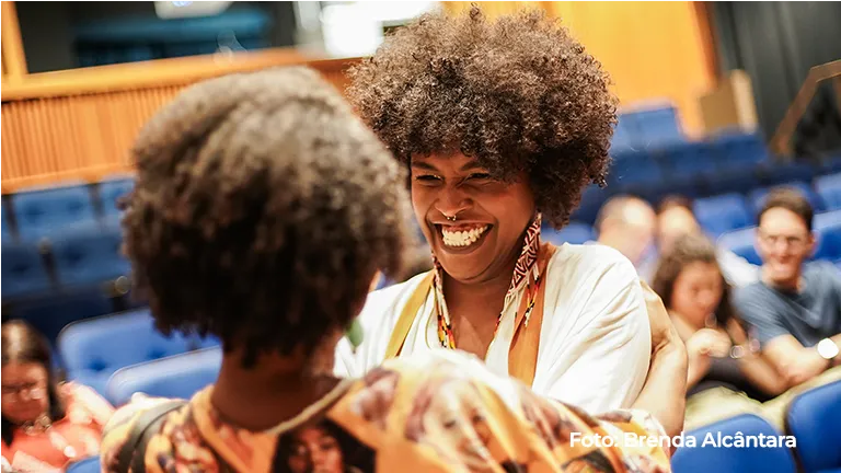 Duas mulheres riem juntas na plateia do teatro