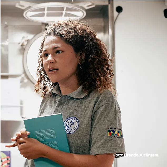 Educadora segura uma publicação a bordo do navio