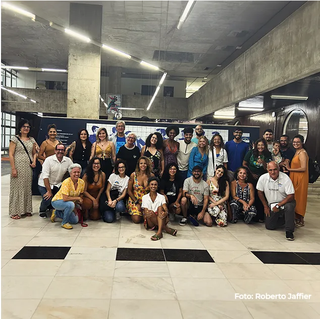 Grupo numeroso posa sob a estrutura de concreto do espaço