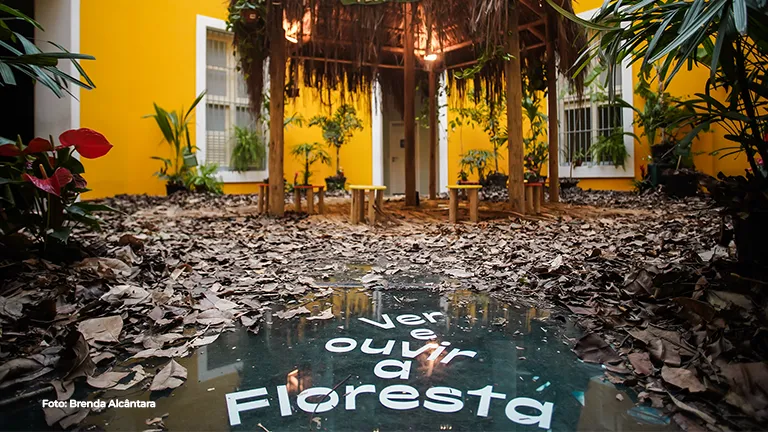 Pátio com o letreiro “Vamos ouvir a Floresta” no chão