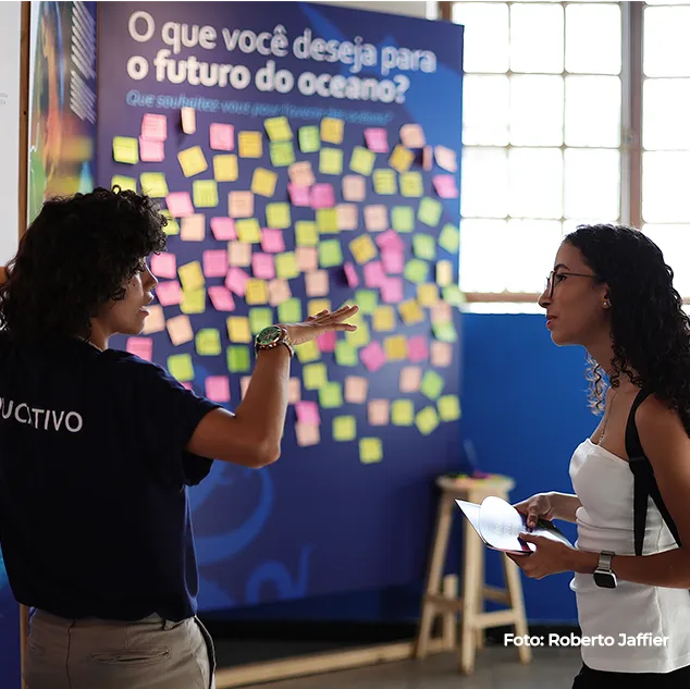 Duas mulheres diante de painel coberto de post-its sobre o futuro do oceano