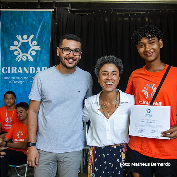 Duas pessoas recebem certificado ao lado do painel do Cirandar