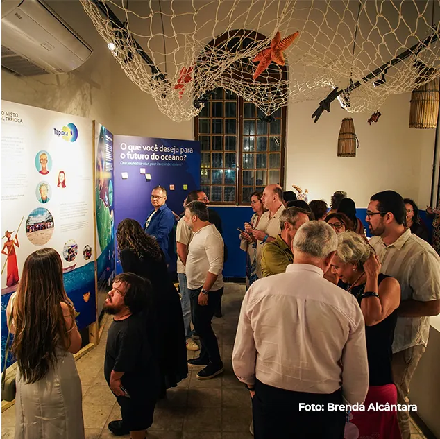 Público reunido diante dos painéis na abertura da exposição