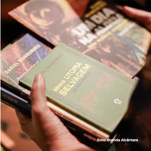 Mãos seguram livros de literatura indígena